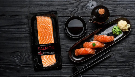 Best salmon for sashimi shown with sliced nigiri, soy sauce, wasabi, and pickled ginger on a black platter.