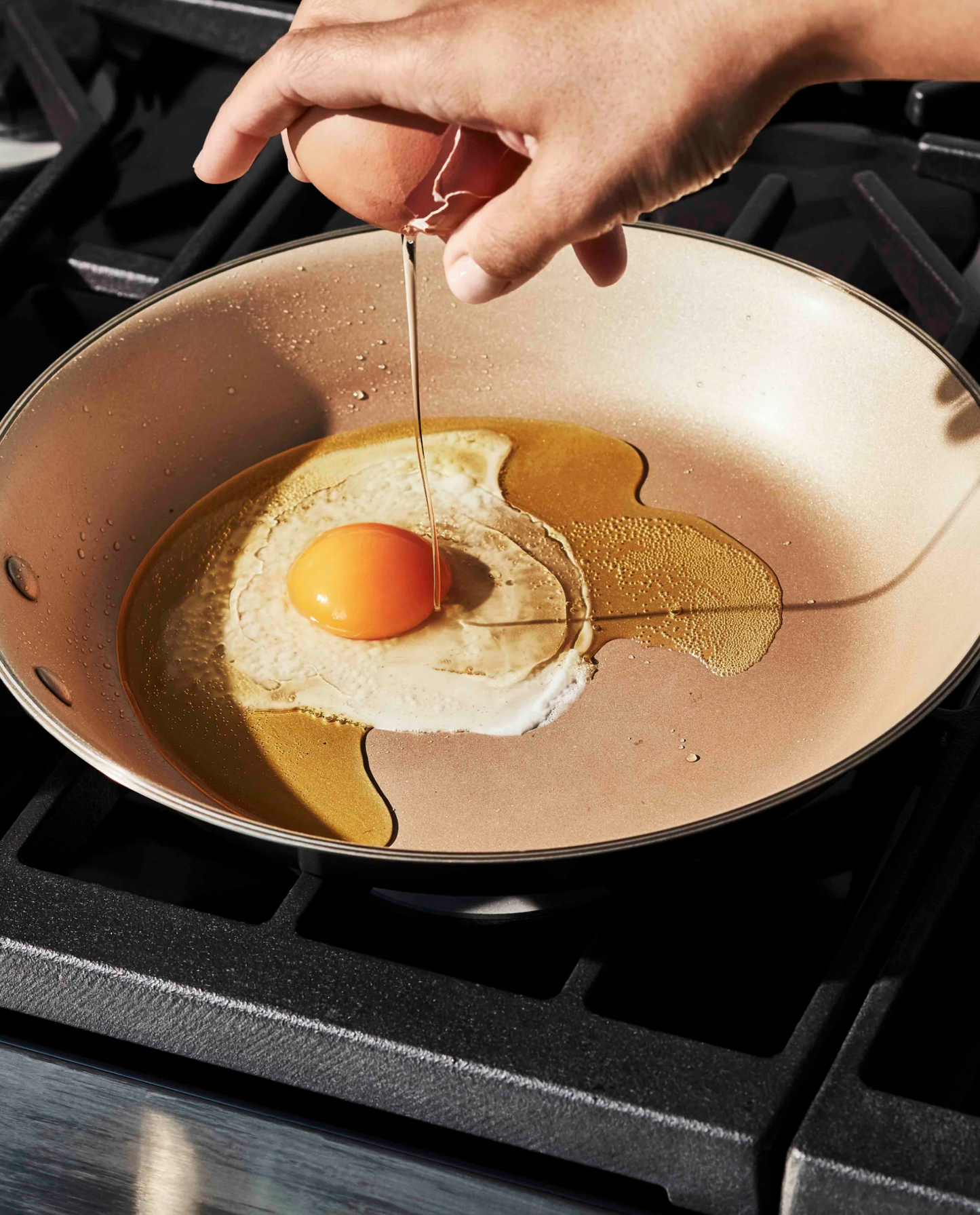 Copper-coated pan with sunny-side-up fried egg and melted butter on a gas stovetop