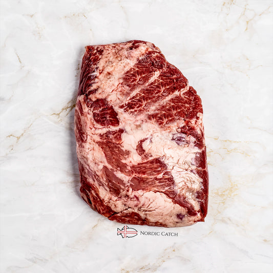 A raw marbled cut of Iberico Presa roast placed on a white marble surface with the Nordic Catch logo printed below.