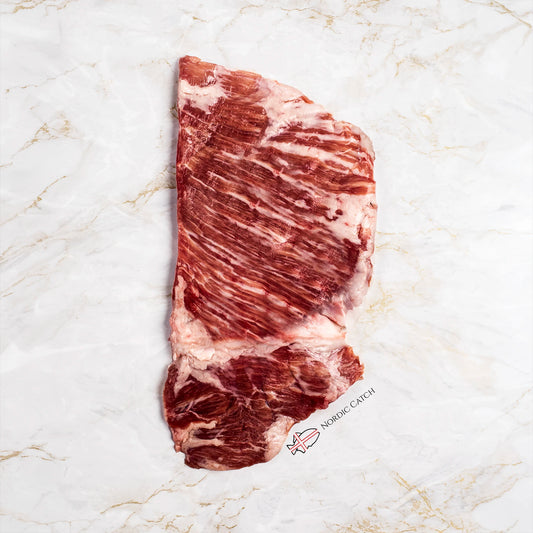 A raw marbled cut of Iberico secreto steak laid flat on a white marble surface. A small 'NORWICH CATCH' logo is printed near the bottom right of the meat.