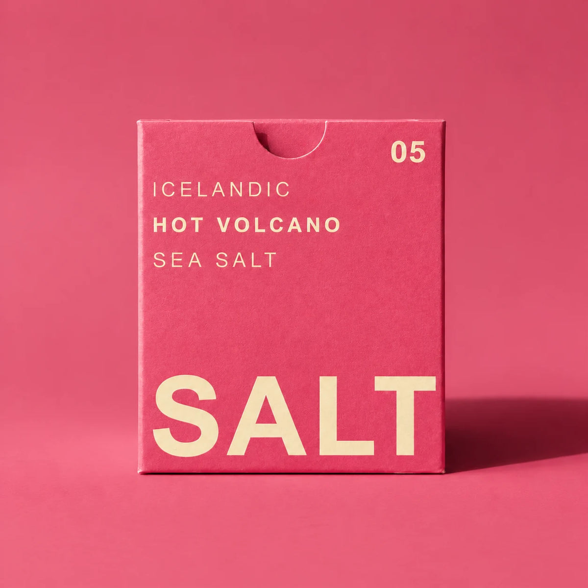 A pink rectangular box of Iceland Hot Volcano Sea Salt with cream-colored text, standing on a matching pink background.