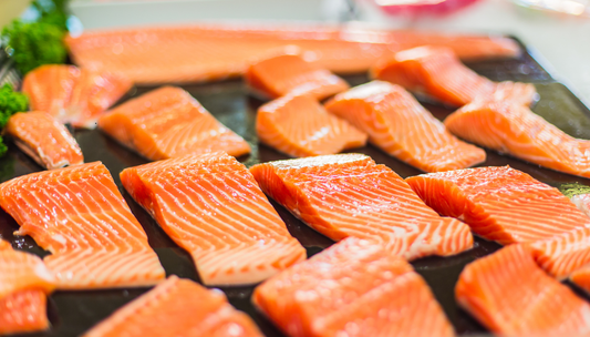 Atlantic salmon fillets arranged on black slate with fresh parsley garnish