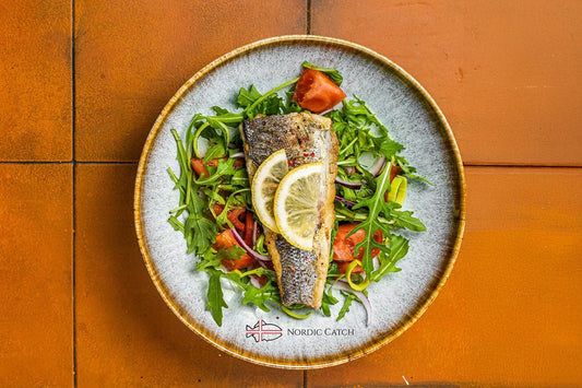 Gourmet branzino fillet on bed of greens with lemon garnish