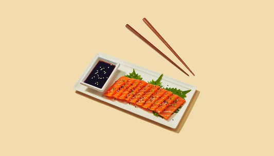 Plant-based seafood sashimi slices served with soy sauce and sesame seeds on a clean plate.