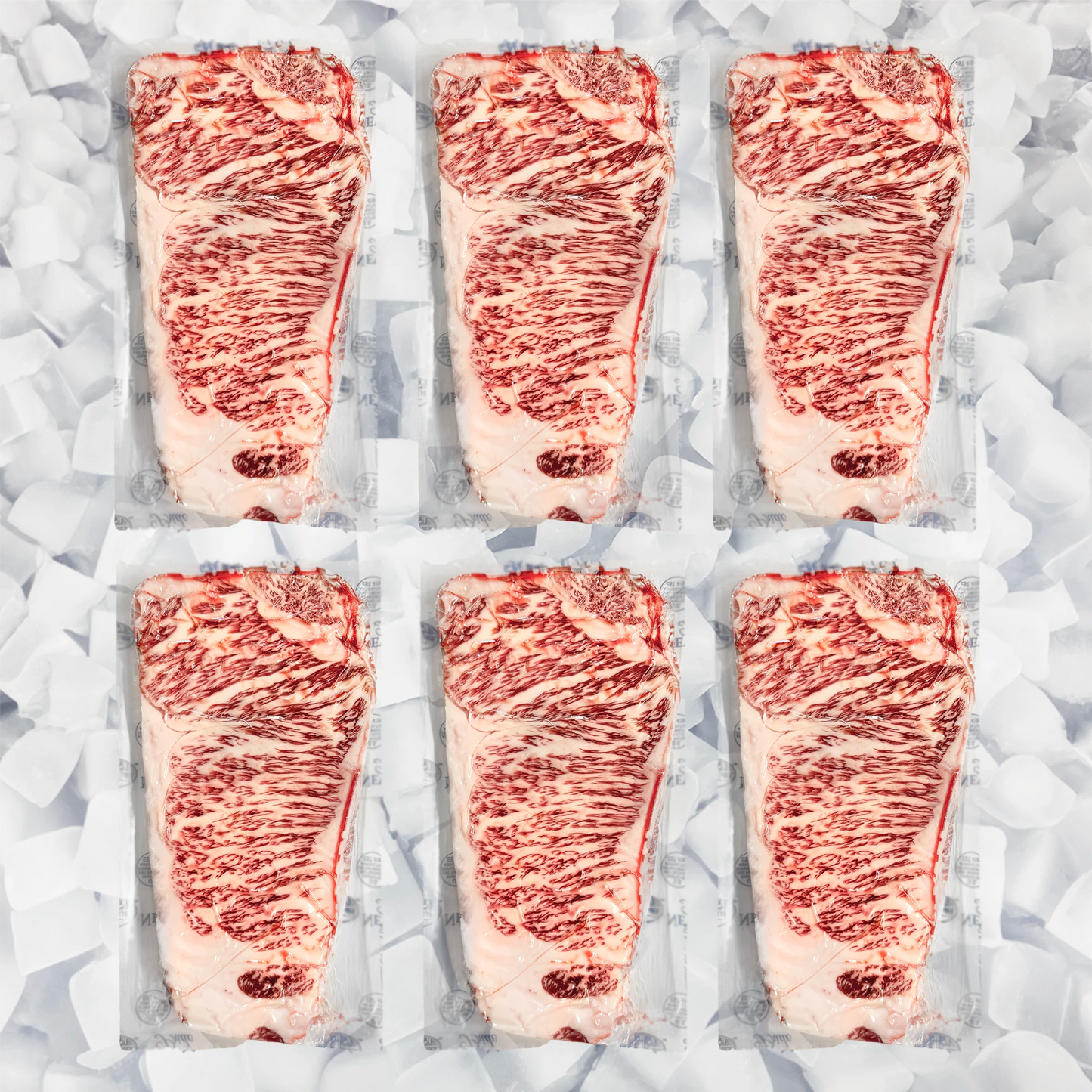 Six raw marbled wagyu NY strip steaks in clear plastic packaging arranged in two rows on a bed of ice cubes.