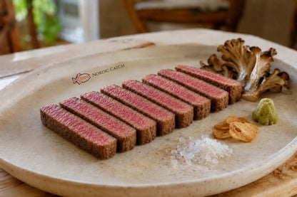Sliced cooked wagyu NY strip steak on a round beige serving platter with mushrooms, chips, salt, and wasabi, branded with the Nordic Catch logo.