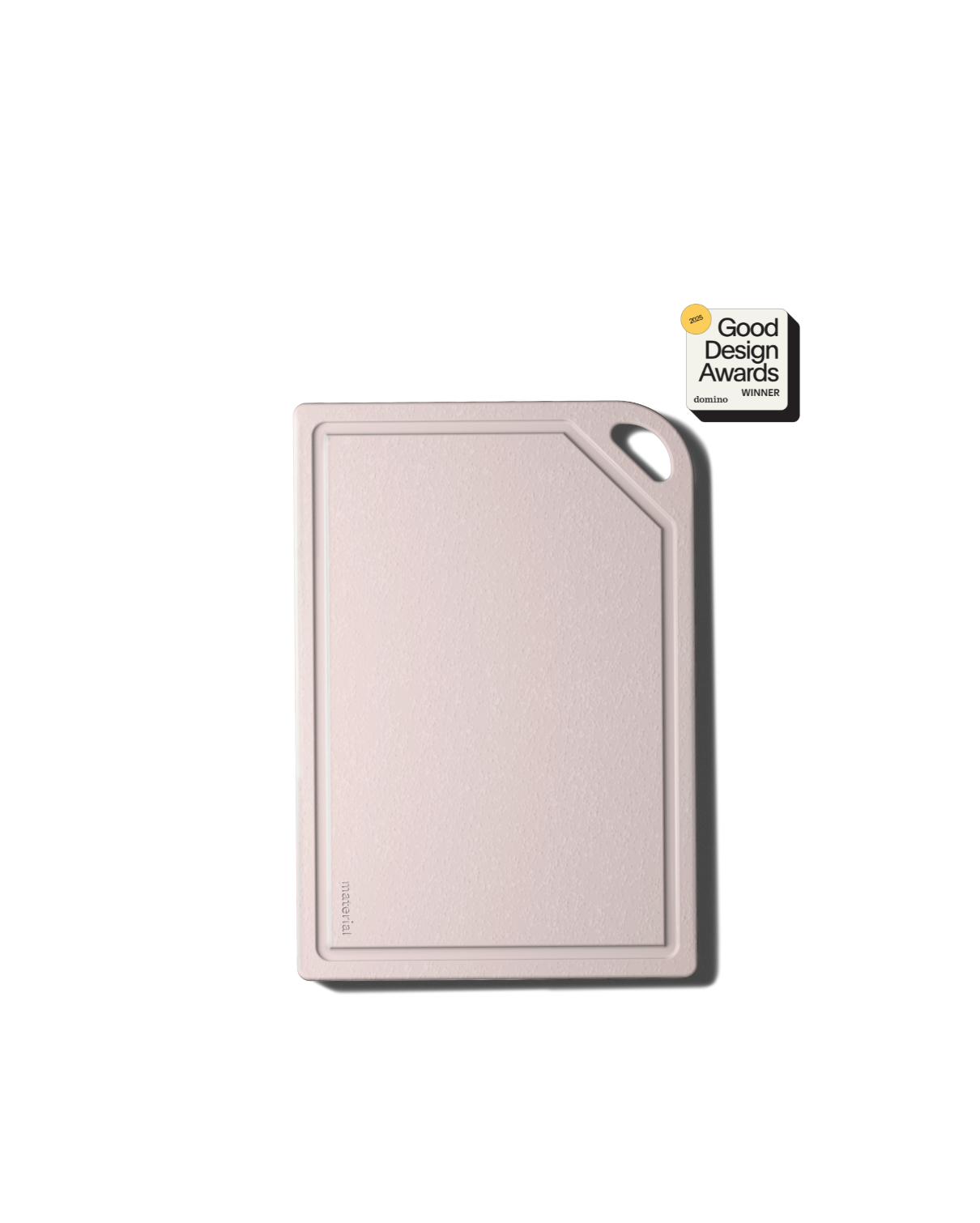 Light pink cutting board with juice groove and black handle displaying Good Design Awards winner certification badge on black background