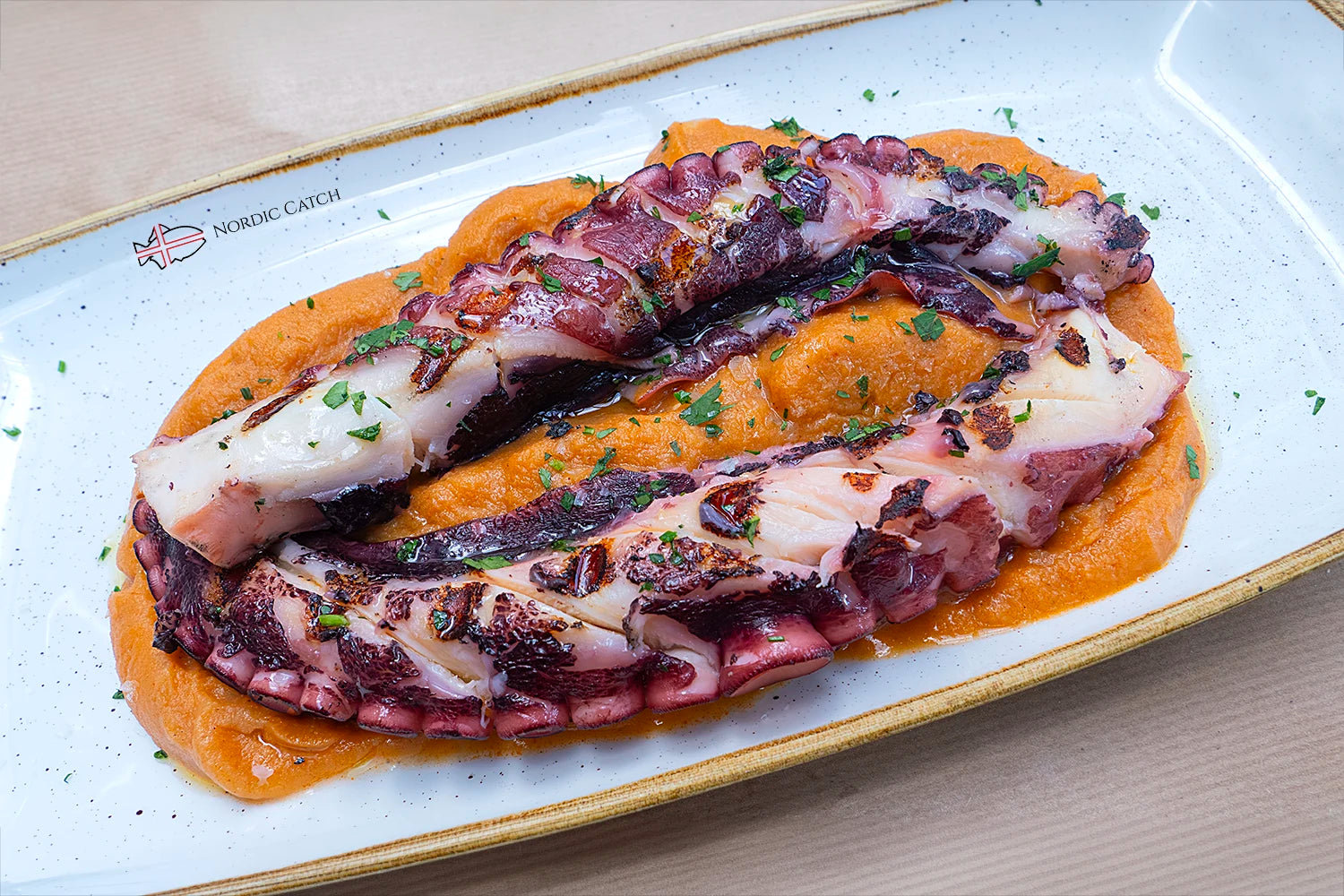 Plated dish of grilled octopus on a white plate with a visible brand logo.