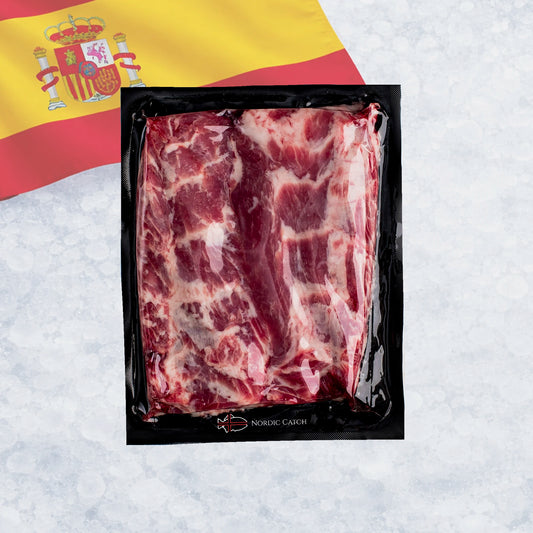 Packaged raw Iberico pluma steak in a black vacuum pack with a Spanish flag graphic in the background.