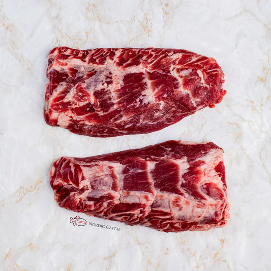 Two raw marbled Iberico pluma cuts, arranged vertically on a white marble surface with a small 'NORIC CATCH' logo near the bottom.