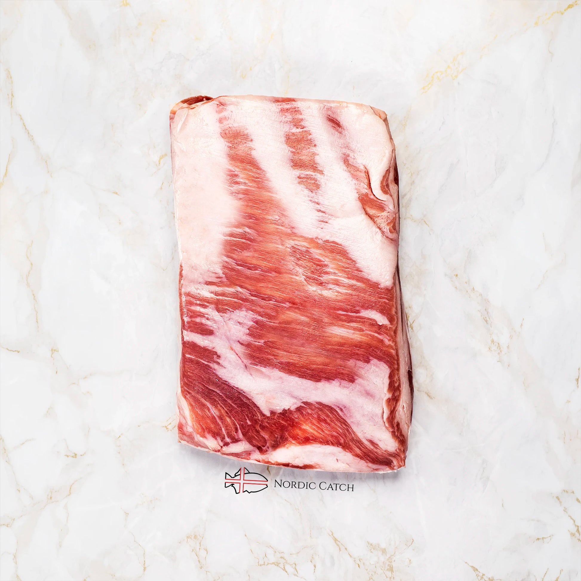 A rectangular cut of raw Iberico pork belly, likely a pork belly or similar fatty cut, displayed on a white marble surface with the Nordic Catch logo printed below.