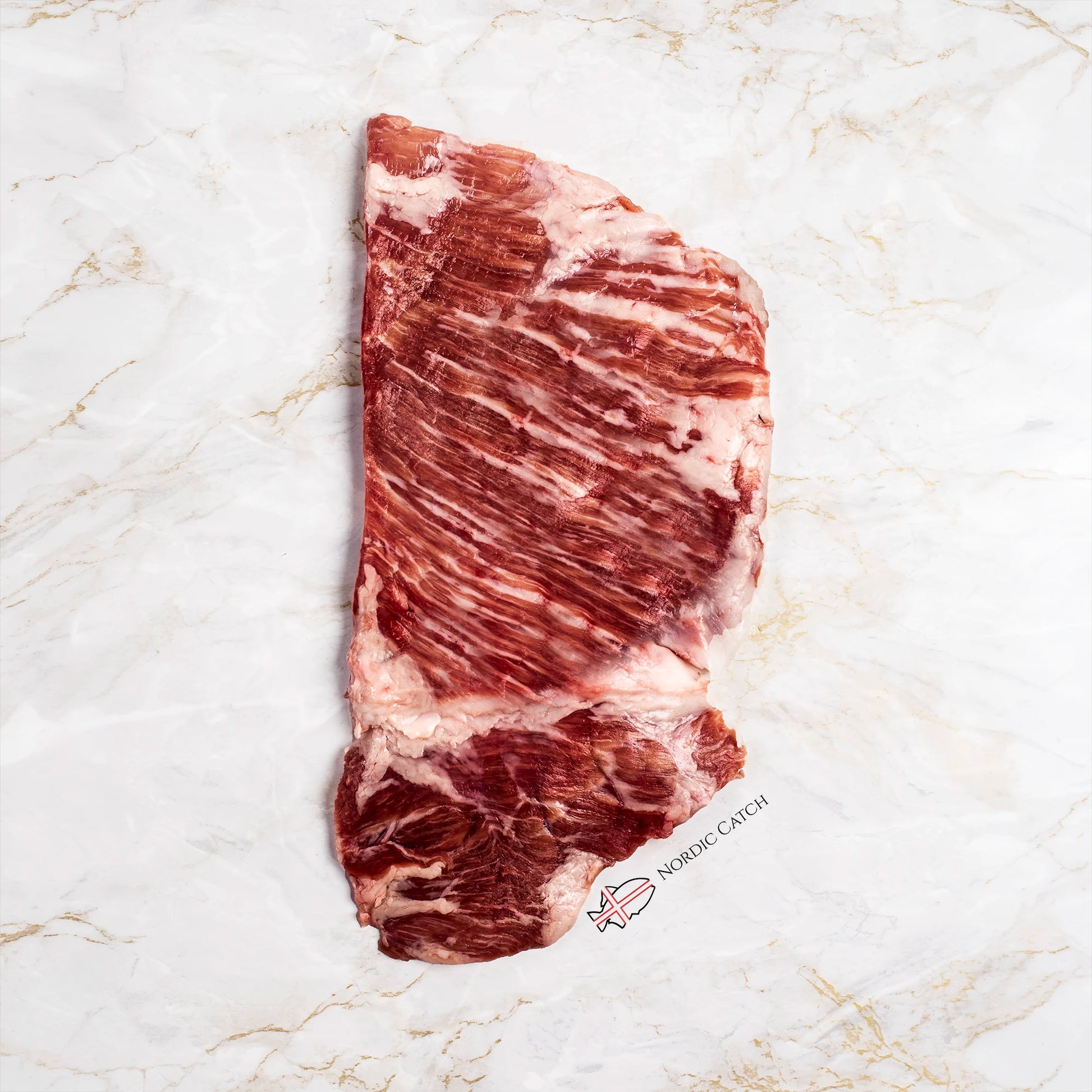 A raw marbled cut of Iberico secreto steak laid flat on a white marble surface. A small 'NORWICH CATCH' logo is printed near the bottom right of the meat.