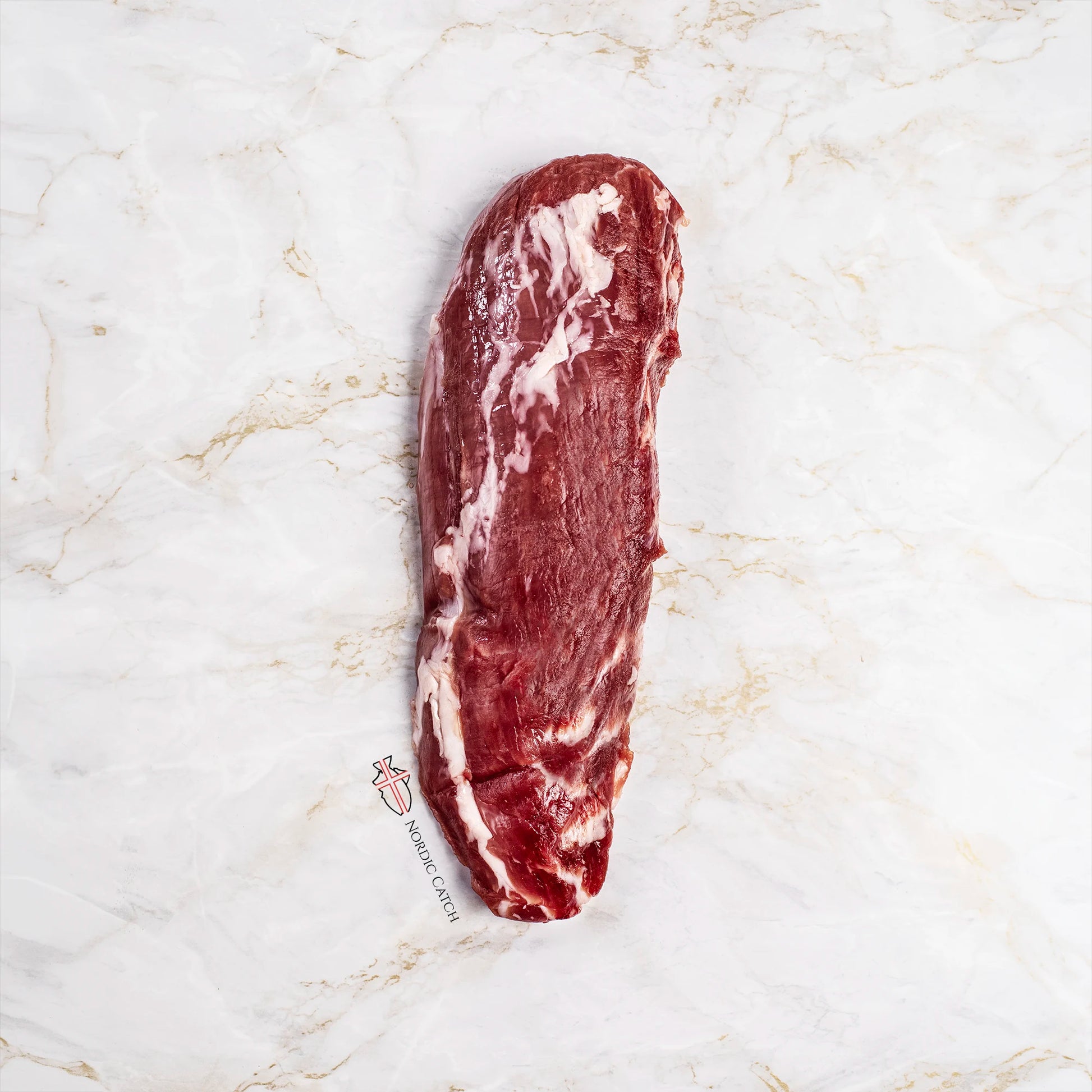A single raw cut of Iberico solomillo tenderloin placed on a white marble surface. A small 'Nordic Catch' logo watermark is visible near the bottom left of the meat.