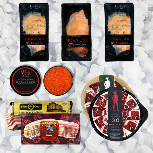 A curated food gift assortment on a white crumpled-paper background, including three packaged salmon fillets labeled Gravlax, Nova Lox, and Arctic Fish; a round tin of Hokkaido Spiny Ruka caviar; a bowl of bright orange roe; Peter Richter smoked turkey bacon; a package of sliced bacon; and a round package of Montiazal Salado beef jerky.