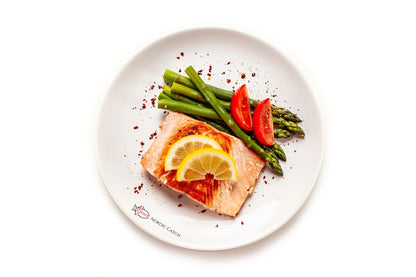 Salmon dish with asparagus and tomatoes on a white plate