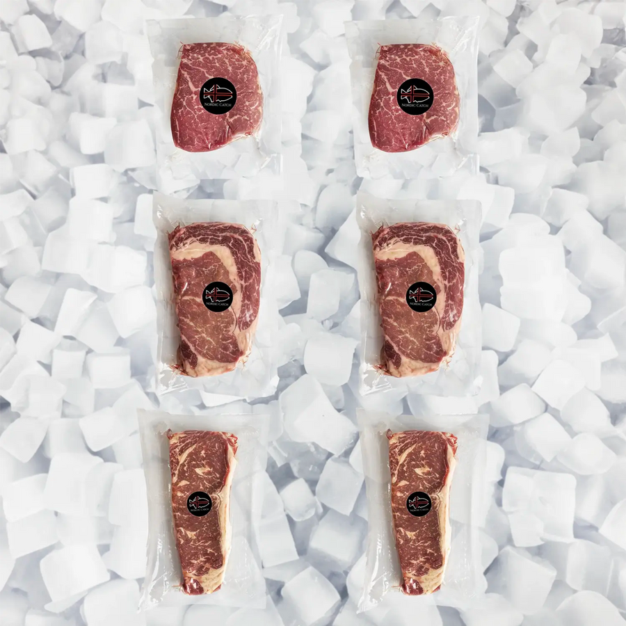 Five vacuum-sealed packages of raw marbled meat arranged in a grid on white ice cubes. Each package has a black oval with a Nordic Catch logo label in the center.