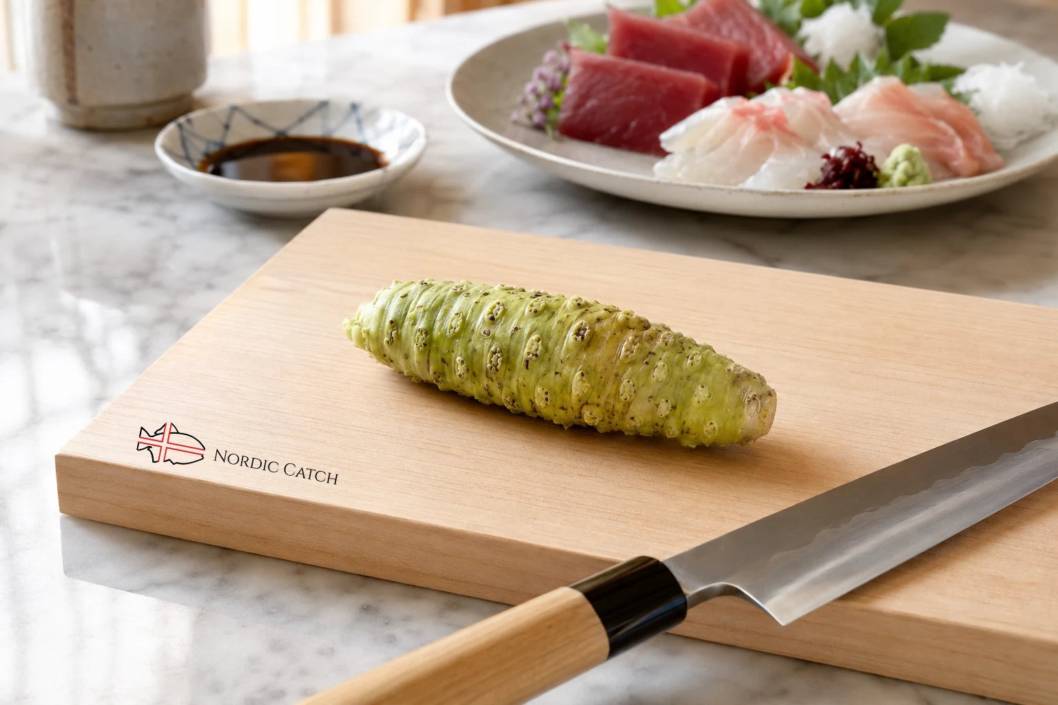 A wooden cutting board with the Nordic Catch logo, featuring a green wasabi rhizome on top and a knife handle resting diagonally. In the background, a plate of fresh sashimi and a small dipping sauce dish are visible on a marble countertop.