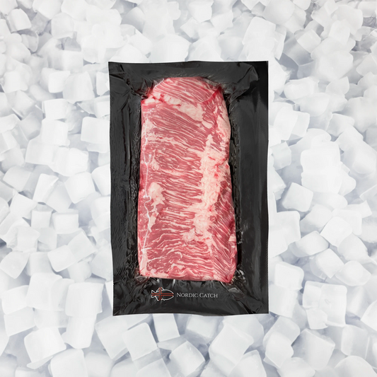 A vacuum-sealed raw cut of marbled skirt steak in a black package, centered on a bed of white ice cubes. The package shows the brand name 'NORDIC CATCH' at the bottom.