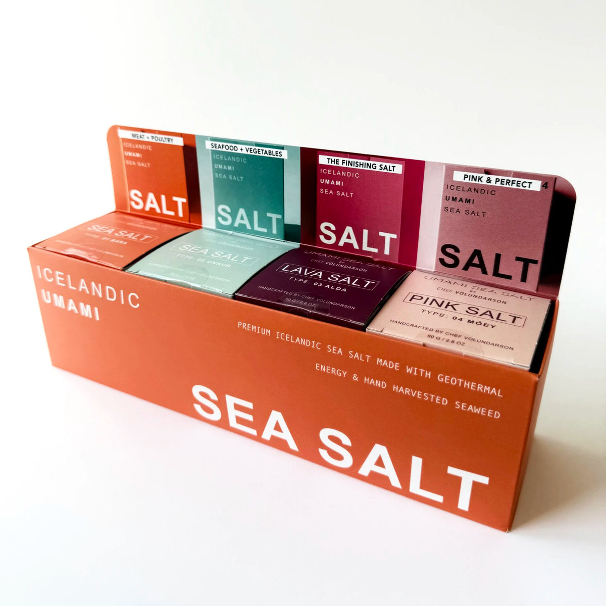 A retail gift box filled with small packaged sea salt boxes from the brand Umami. The display box is orange and reads 'SEA SALT' in large white letters, with several individual salt packs visible behind it in different colors including orange, teal, purple, and pink.