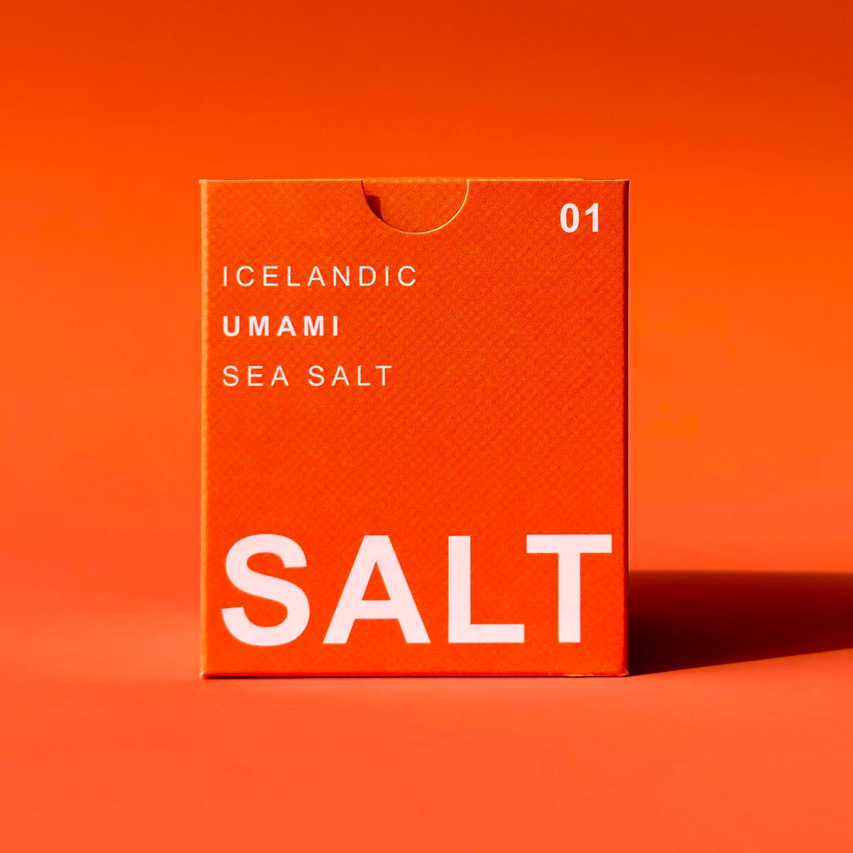 A bright orange square box of Icelandic Umami Sea Salt with white text, standing on a matching orange background.