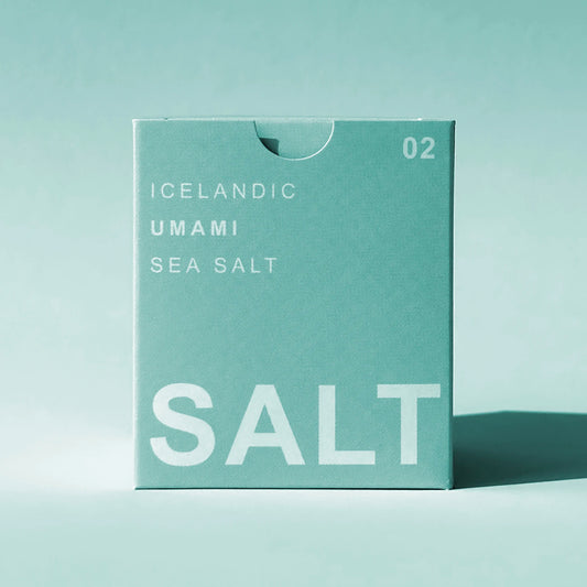 A square mint-green box of Icelandic Umami Sea Salt with white text, standing upright on a matching mint-green surface against a light teal background.