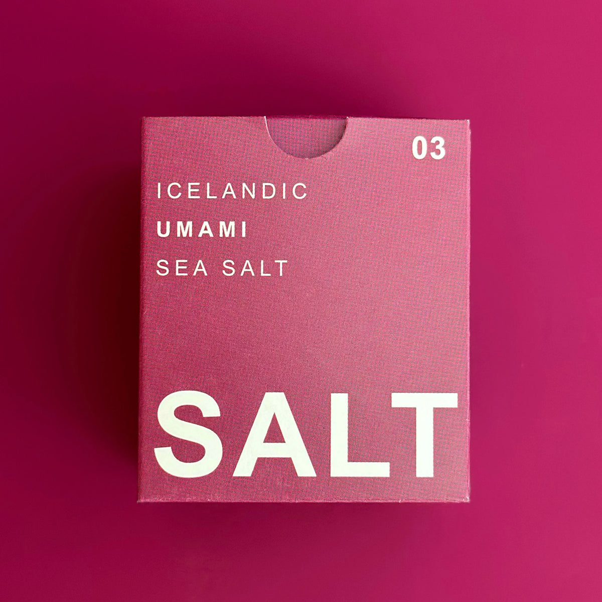 A square pink box of Icelandic Umami Sea Salt with white text, displayed on a matching solid pink background.