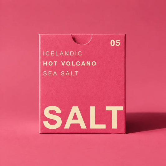 A pink rectangular box of Iceland Hot Volcano Sea Salt with cream-colored text, standing on a matching pink background.