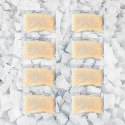 Eight vacuum-sealed packages of salmon fillets arranged in two columns on a bed of white ice cubes. The salmon has a light orange-pink color typical of fresh salmon, and each package has a small red logo on the top left.