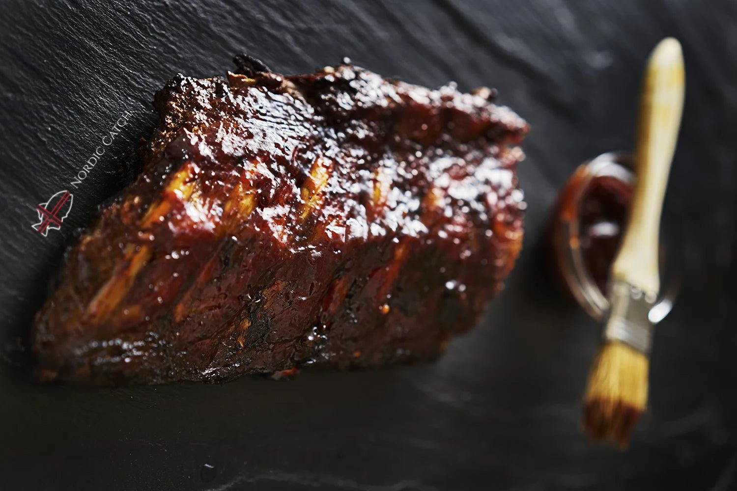 Grilled rib with barbecue sauce and brush on a dark surface