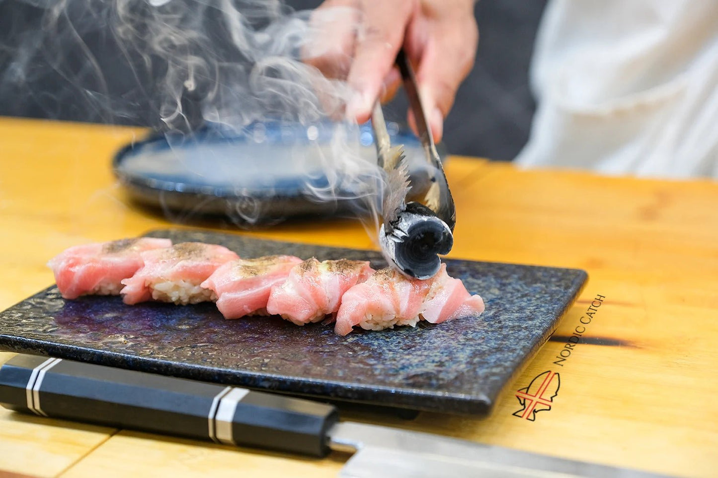 Person preparing Bluefin Otoro on a cutting board with a knife and fork.